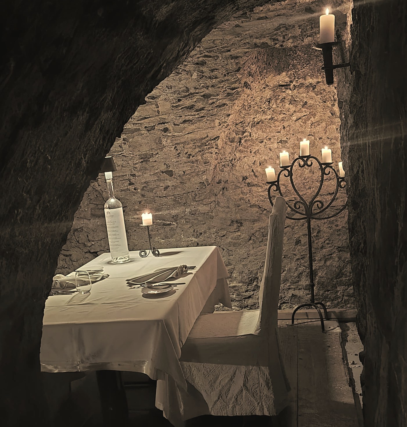 Table pour deux aux chandelles dans une cave voûtée, l'ambiance d'un événement privé avec musique live